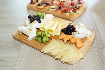 The buffet at the reception. Assortment of canapes on wooden board. Banquet service. Catering, snacks with different types of cheese and meat. Party Concept.