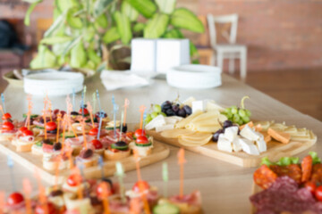 The buffet at the reception. Assortment of canapes on wooden board. Banquet service. Catering, snacks with different types of cheese and meat. Party Concept.