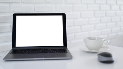 Close - up shot of Mockup laptop screen blank with white coffee in modern cafe.