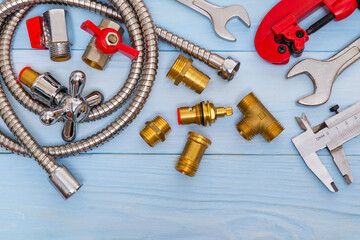 Necessary set of tools and spare parts for plumbers on blue wooden background