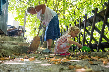 Cute girl helping her grandmother clean around the house.