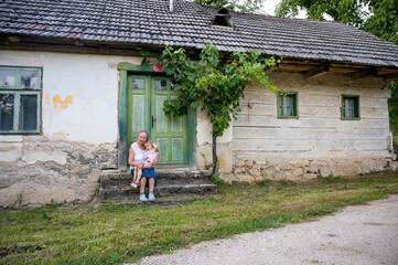 Fototapeta na wymiar Grandmother sitting with her grandmother in front of her old house.