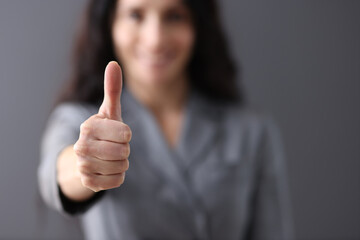 Modern business woman showing thumb up in office closeup