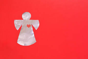 Foil-cut angel figurine on a red background. Place for text about Valentine's Day, love, religion...