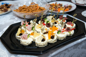The buffet at the reception. Assortment of canapes on a table. Banquet service. Catering food, snacks with different types of cheese, ham, salami, prosciutto, shrimp, vegetables and fruits. 