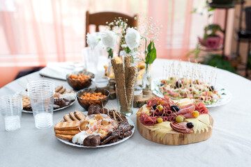 The buffet at the reception. Assortment of canapes on a table. Banquet service. Catering food, snacks with different types of cheese, ham, salami, prosciutto, shrimp, vegetables and fruits. 
