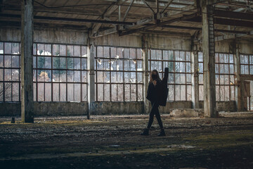 young tall girl with a guitar walks through an abandoned room