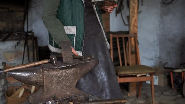 Forge workshop. Smithy manual production smith with hammer hit scoop, on the anvil Forging process. Blacksmith makes iron products for manufacture of fireplace, stove.