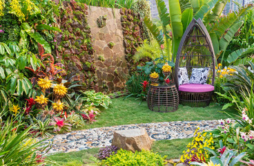 Fototapeta na wymiar Cozy seat in decorated backyard flower garden
