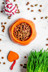 dry cat food in bowl on stone background top view