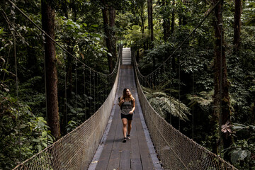 woman traveler walking across rope bridge in costa rica jungle
