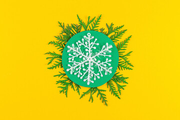 Christmas composition with coniferous tree branches on yellow paper background. Round frame of Christmas tree branches and decorations with space for text. Top view. New year concept