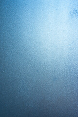 Vertical image of a winter background on a transparent glass window with a frozen texture. Abstract texture background, vertical photo, copy space for your design or text