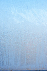 Vertical image of a winter background on a transparent glass window with a frozen texture. Abstract texture background, vertical photo, copy space for your design or text