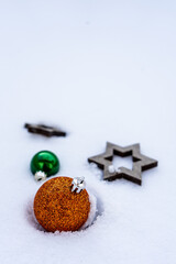 Eine goldenen Christbaum Kugel und zwei Holz Sterne im weißen Schnee. Nahaufnahme, Weihnachten, Winter.