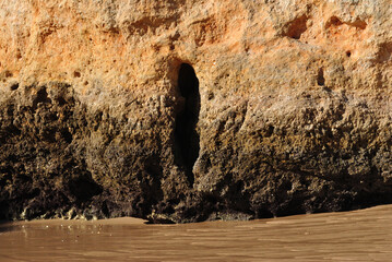 Close Up of Small Cave in Rock Cliff on Sandy Beach 