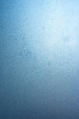 Vertical image of a winter background on a transparent glass window with a frozen texture. Abstract texture background, vertical photo, copy space for your design or text