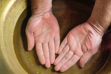Male hands palms up. Copper bowl with clean water. Top view. Hand care concept. Pure water concept. 