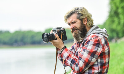 Masterpiece shot. Man bearded hipster photographer hold vintage camera. Photographer amateur photographer nature background. Man with beard shooting photos. Photographer concept. Content creator