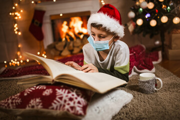Fototapeta na wymiar Boy meets Christmas in the covid-19 pandemic. Child in a protective medical mask. Quarantine isolation social distance. New year holidays.