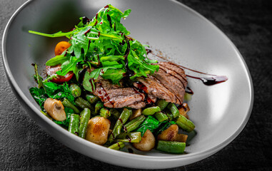 Roastbeef salad with green beans and mushroom in a bowl on Dark grey black slate background