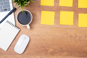Workplace of office desk wooden table with Yellow post notepaper, memo paper on a top table desk, scheduled for job or short note for work concept, minimal office desk