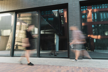 motion blur of citizens walking on modern street near building