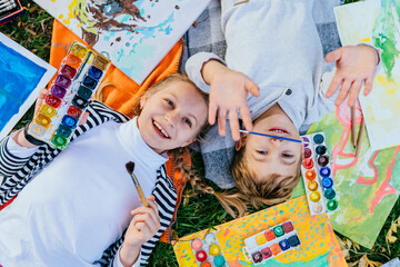 Girl and boy are drawing and painting in the park. They use their imagination and creativity in...