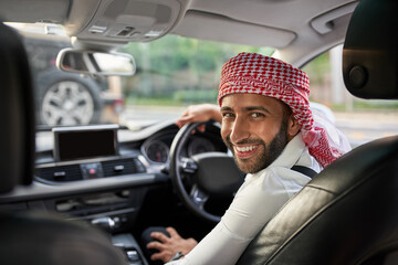 Arab ehailing driver smiling looking back at passengers of taxi cab