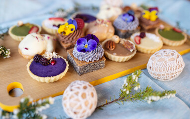 Selection of colorful and delicious cake desserts on tray on table.
