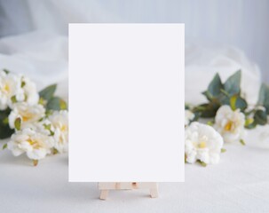 White empty vertical card mockup, wedding invitation template, menu card, white flowers on background.