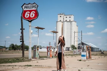 Poster woman walking through abandoned gas station on route 66 © Zach