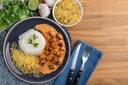 Chicken stroganoff with rice and french fries on a plate, over rustic wooden table. Top view. Space for text