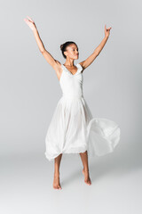barefoot graceful african american ballerina in dress dancing on white background