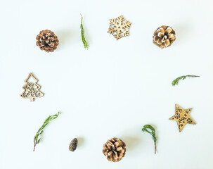 Arrangement of wooden christmas ornaments, pine cones and pine branches on an isolated white surface with copy space, top view
