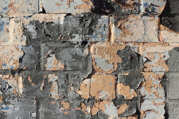 Shabby old brick wall with peeling black paint