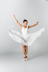 graceful african american ballerina in dress dancing on white background