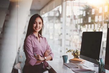 Beautiful confident asian business woman arms crossed and smiling at modern office background. Indoors