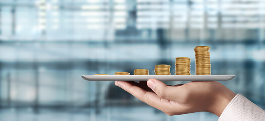 Coins set up in graph, line chart on tablet in hand