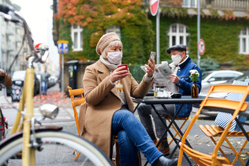 Senior people sitting in outdoor cafe in city, coronavirus concept.