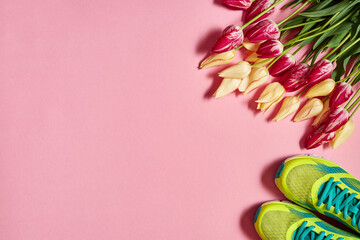 Pair of sport shoes and tulip flowers on pink pastel background, copy space. New sneakers. Overhead shot of running footwear. Top view, flat lay. Spring, sport, minimal concept