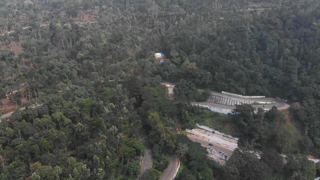 Yercaud highway hairpin bend covered with thick lush of trees in the forest. Vehicles moving over the hillside road.