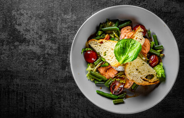 Green Bean Salad with Boiled Eggs, Salmon, Tomatoes and Arugula in a bowl on Dark grey black slate background