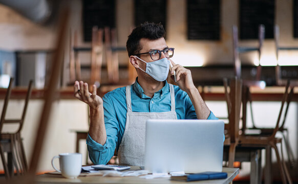 Frustrated owner sitting at table in closed cafe, small business lockdown due to coronavirus.