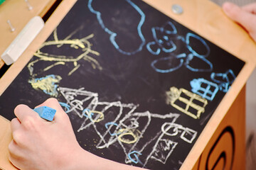 Small boys hands drawing Christmas scene on the chalkboard. Childhood, inspiration, creativity and leisure activity