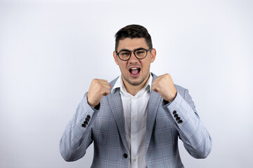 Business young man wearing a casual shirt over white background very happy and excited making winner gesture with raised arms, smiling and screaming for success.