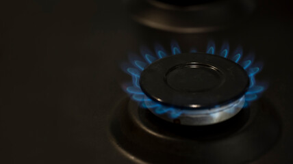 lit gas burner on the gas surface of an anthracite-colored stove