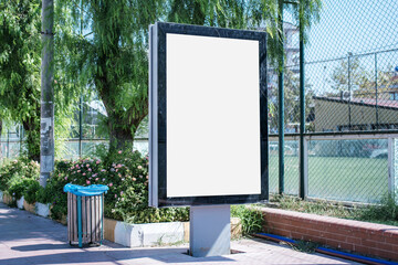 Big empty billboard in black frame with empty white mockup space on sidewalk of city street