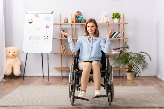Full length of positive psychologist with shrug gesture sitting in wheelchair in office