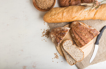 Sliced bread with different kinds of fresh baked bread on a white wooden background. top view, copy space.